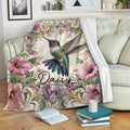 Hummingbird floral throw blanket draped over a sofa with books and a cup nearby