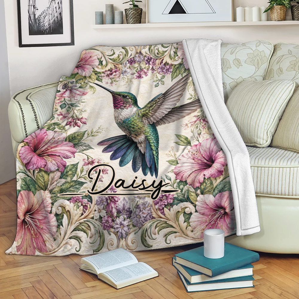 Hummingbird floral throw blanket draped over a sofa with books and a cup nearby