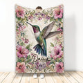 Hummingbird blanket with colorful floral artwork displayed vertically in a bright room