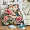 Hummingbird blanket draped over a sofa with tropical floral artwork in a cozy living room