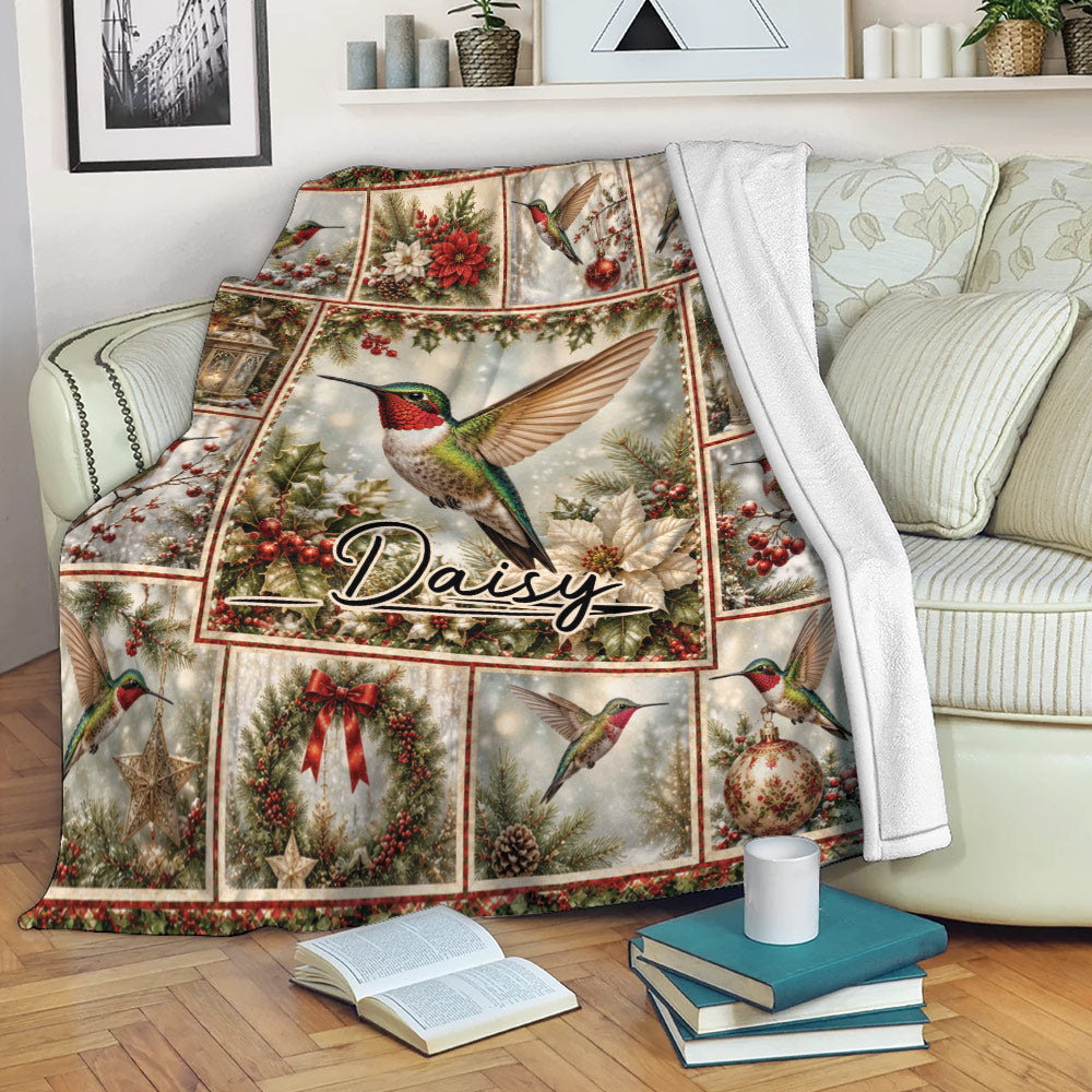 Hummingbird Christmas throw blanket draped over a sofa with festive greenery and red holiday accents
