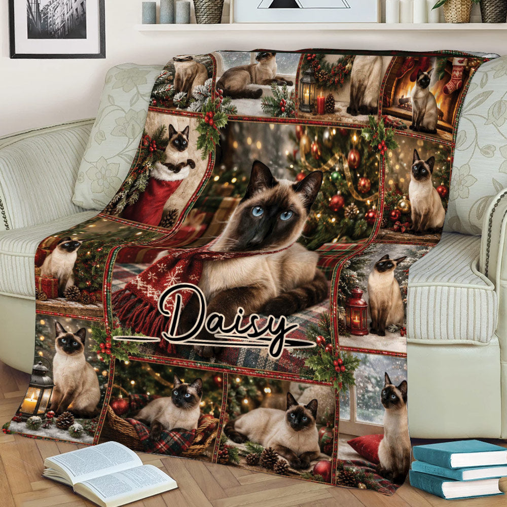 Close lifestyle view of a Siamese cat Christmas blanket styled across a sofa with holiday artwork