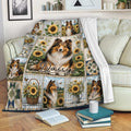 Sheltie blanket draped over a sofa, featuring sunflower scenes, pastoral artwork, and multiple dog portraits