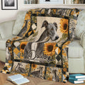 Close view of a Greyhound throw blanket on a sofa featuring sunflowers and multiple Greyhound portraits
