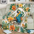 Colorful parrot blanket displayed on a sofa, surrounded by tropical flowers and foliage