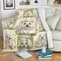 Maltese blanket draped over a sofa with white dog portraits, daisies, and soft green decorative panels