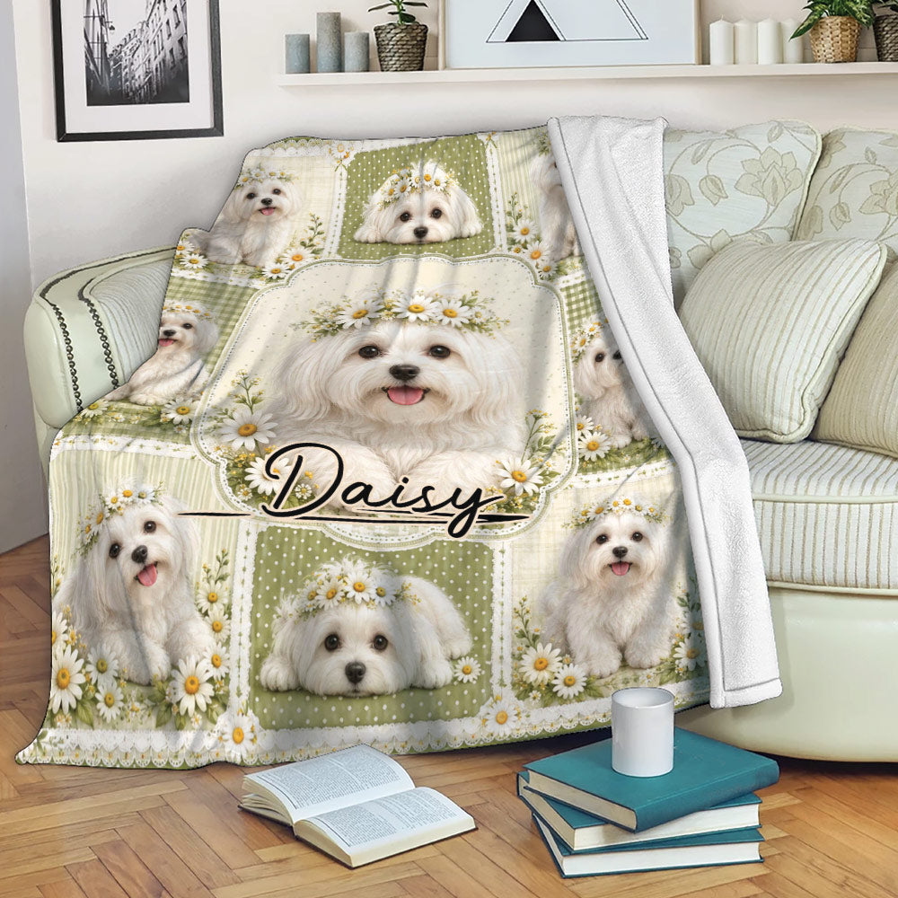 Maltese blanket draped over a sofa with white dog portraits, daisies, and soft green decorative panels