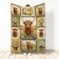 Highland cow blanket displayed upright with floral patchwork artwork in rustic green, gold, and cream tones