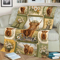 Highland cow blanket styled on a sofa, featuring floral patchwork panels and scenic countryside artwork