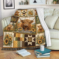 Highland cow throw blanket draped over a sofa with sunflower and rustic patchwork design