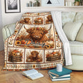 Highland cow blanket draped over a sofa with pumpkins, sunflowers, and cozy fall artwork