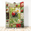 Ladybug blanket displayed upright with red and black ladybugs, daisies, leaves, and botanical collage panels