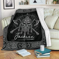 Viking throw blanket displayed on a sofa with a black and white warrior skull design and intricate Norse borders