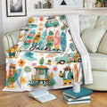 Surfing blanket displayed on a sofa with colorful surfboards, waves, tropical scenes, and beach artwork