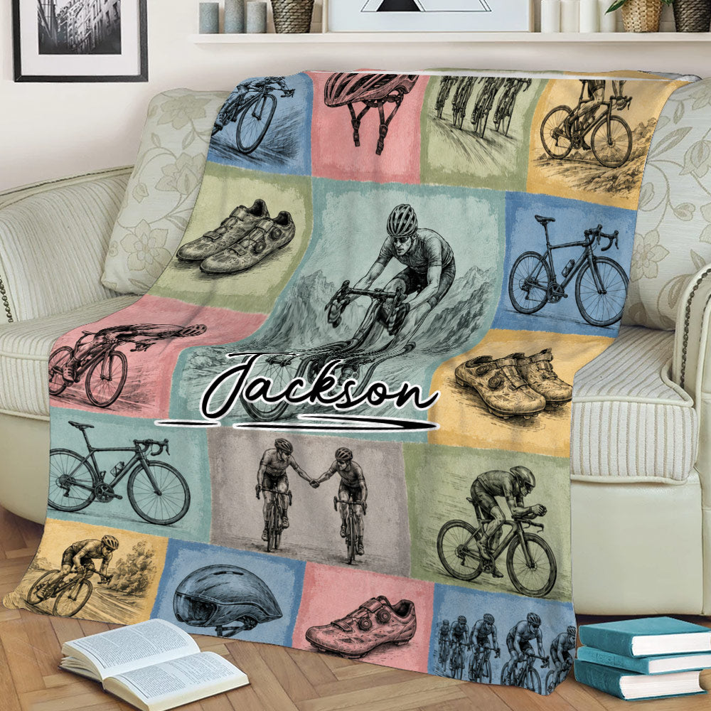 Close view of bicycle throw blanket featuring cyclists, road bikes, helmets, shoes, and mountain riding artwork