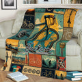 Cycling-themed throw blanket on a couch with illustrated bicycles, bike components, landscapes, and retro colors