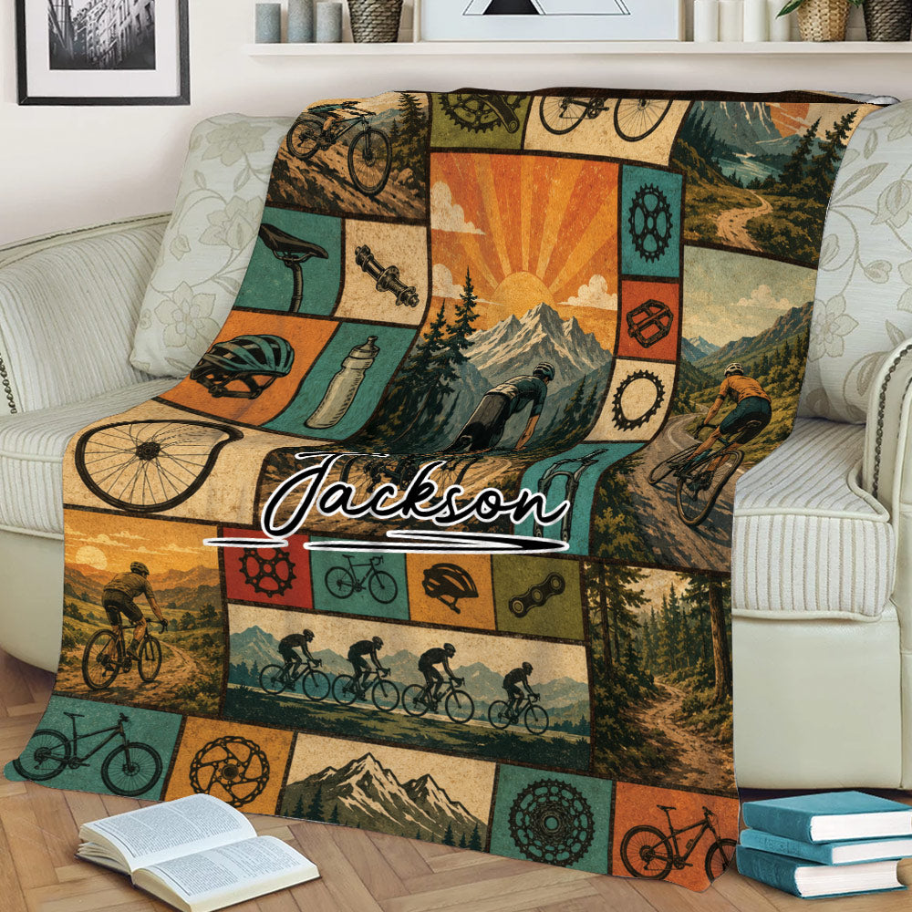 Bicycle blanket draped over a couch, showcasing cyclists, mountain trails, bike parts, and retro outdoor artwork