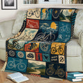 Cycling-themed throw blanket displayed on a couch with bicycle illustrations, mountain scenery, and bike parts