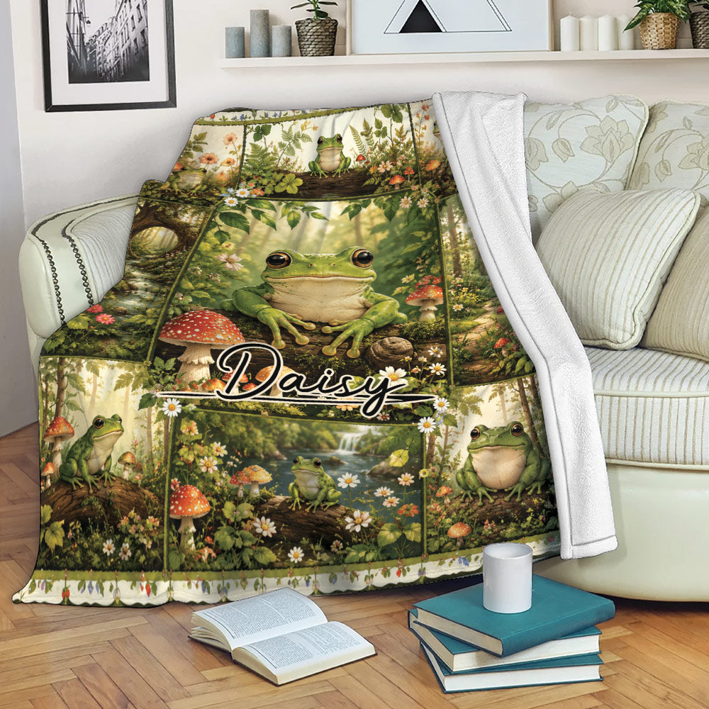 Frog throw blanket draped over a sofa with woodland scenes, flowers, mushrooms, and green frogs