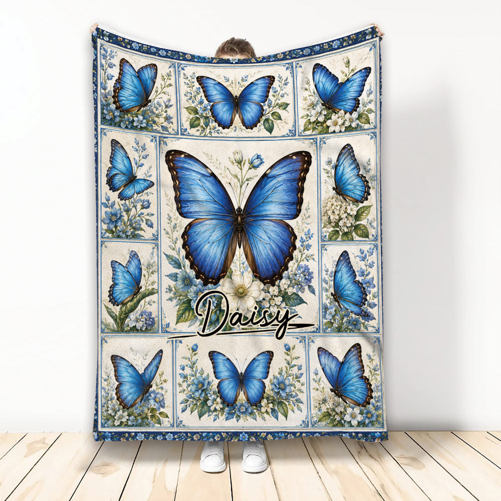 Blue butterfly throw blanket with floral panels displayed against a light wall