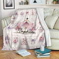 Ballet blanket draped over a sofa with ballerina, pointe shoe, floral, and bow artwork