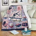 Custom gymnastics blanket draped over a sofa with gymnast artwork, gym equipment, stars, and pink navy colors
