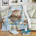 Otter blanket draped over a sofa, featuring floral river artwork and a cozy living room setting