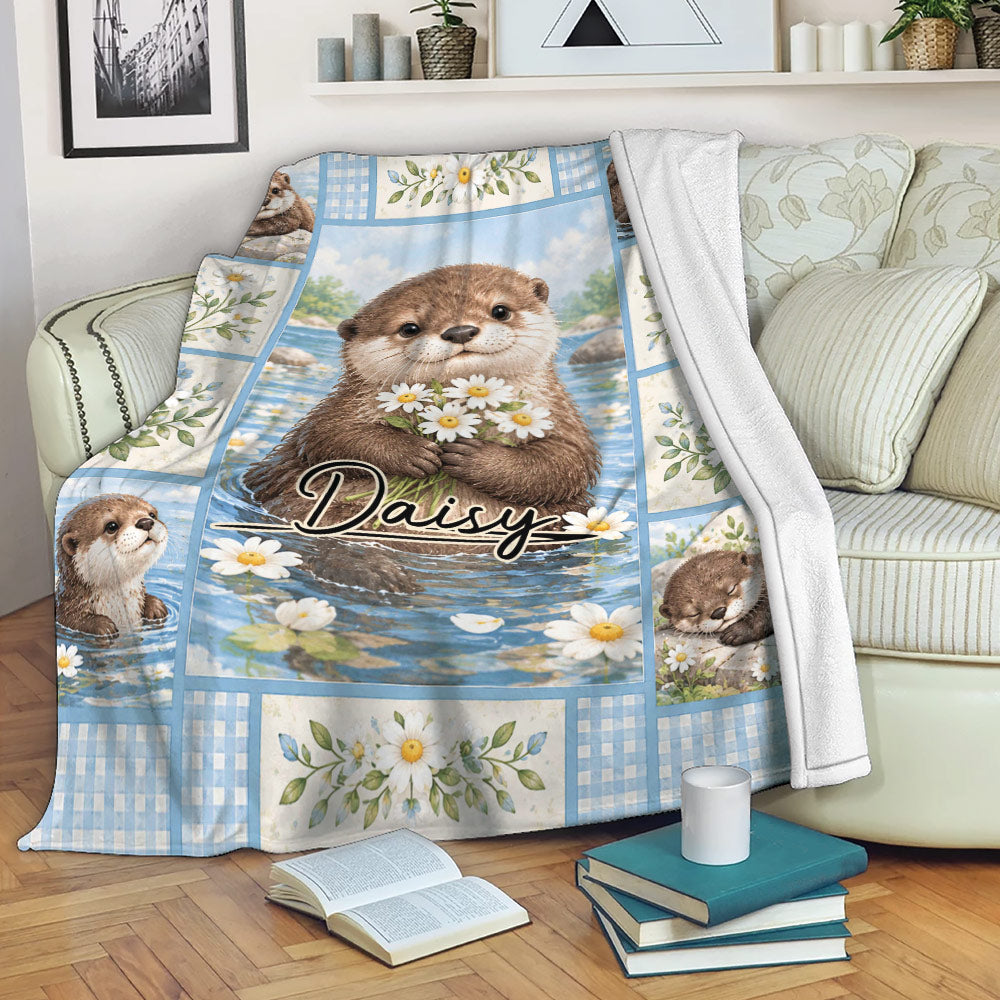 Otter blanket draped over a sofa, featuring floral river artwork and a cozy living room setting