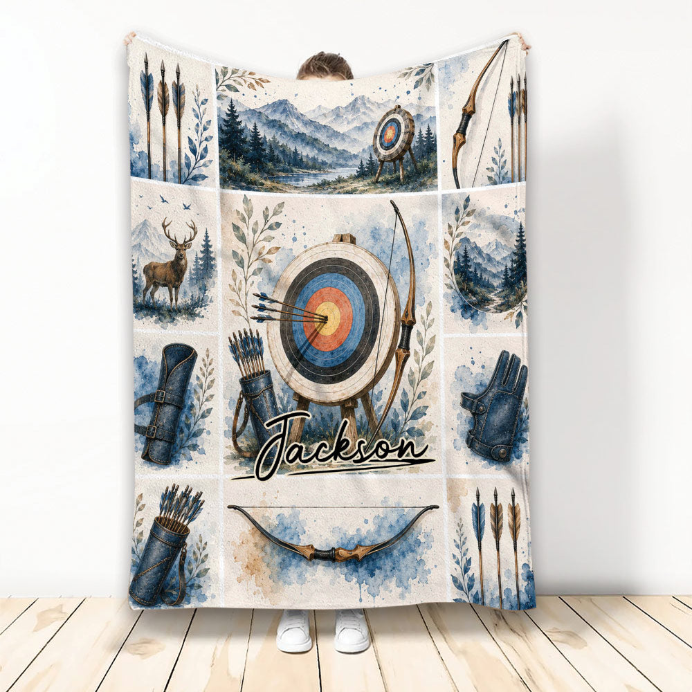 Archery blanket held up showing watercolor bows, arrows, target, mountain landscape, and deer artwork