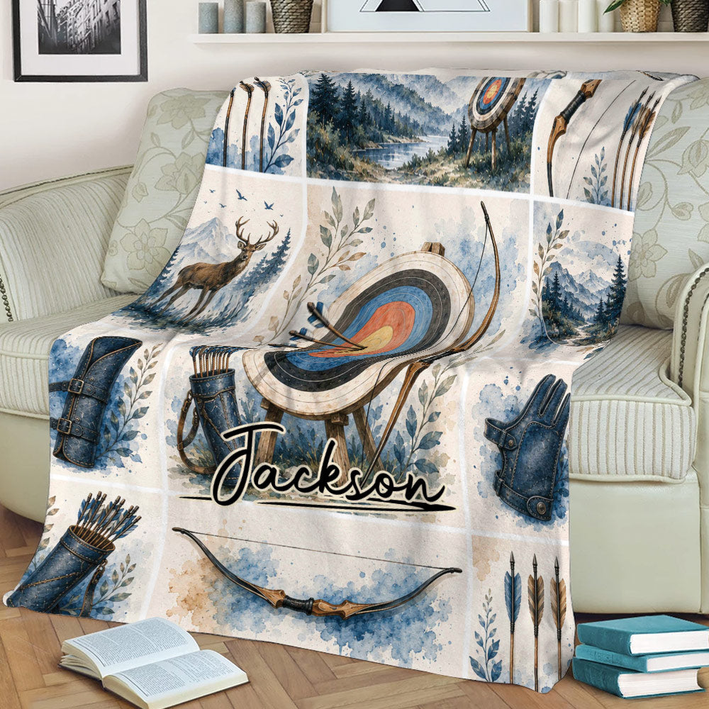 Close view of an archery throw blanket on a sofa with target, bows, arrows, and scenic artwork