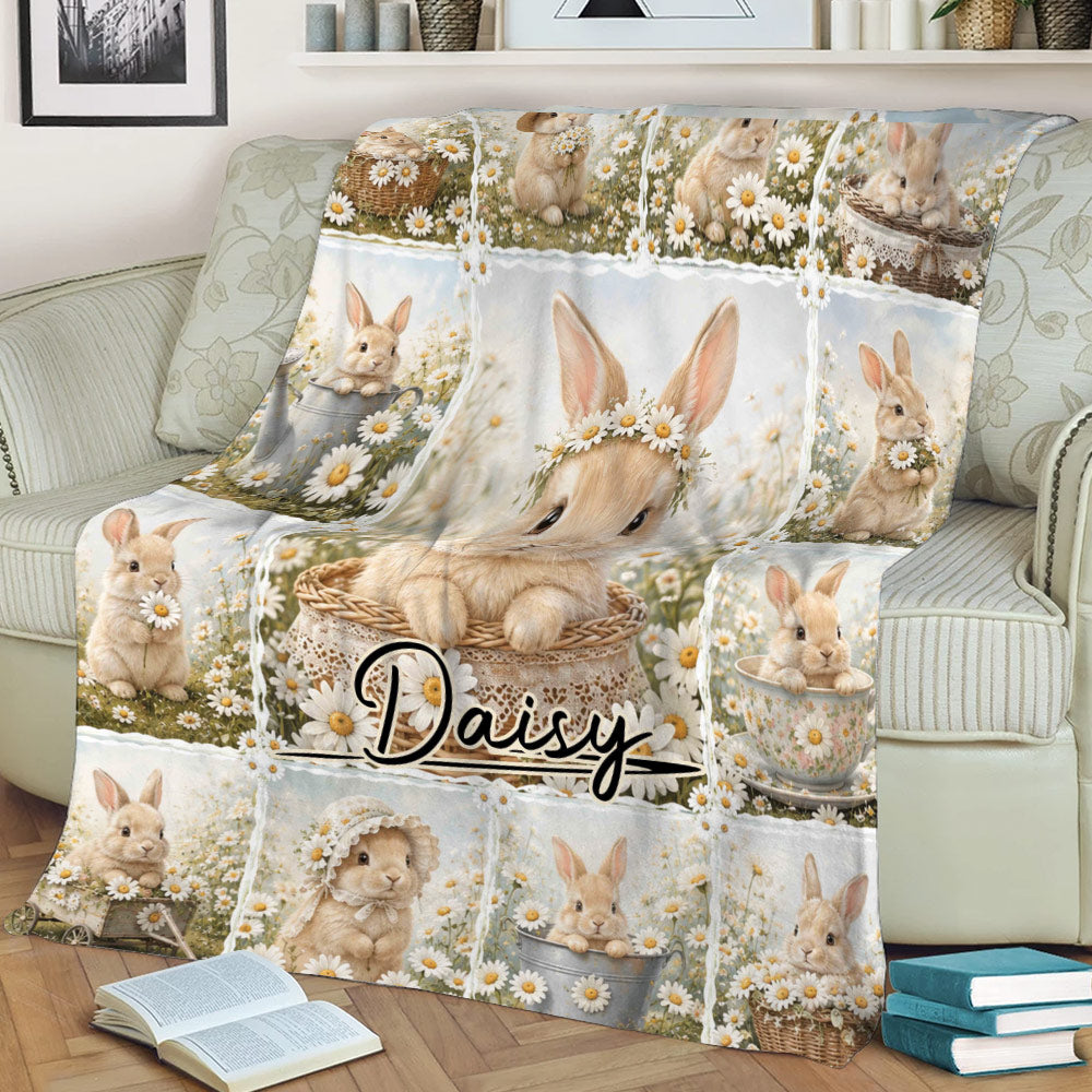 Floral rabbit throw blanket displayed on a sofa with whimsical bunny scenes and daisy artwork