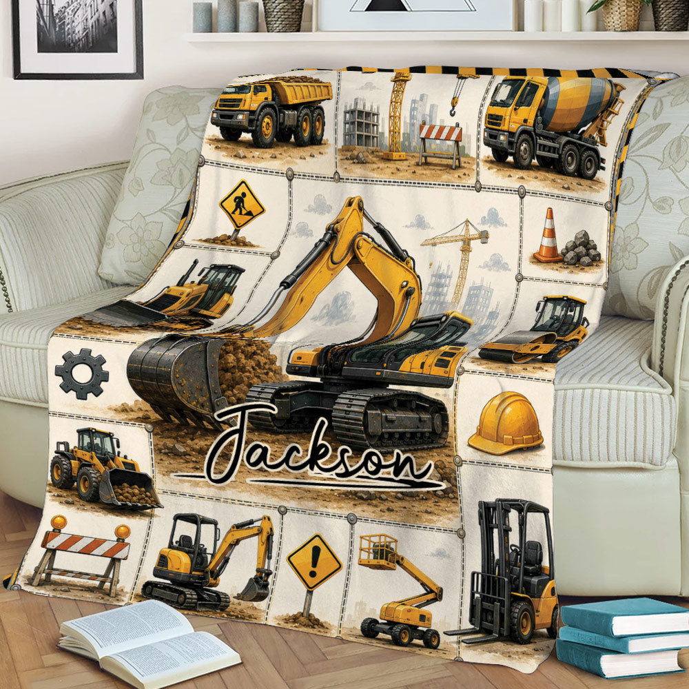 Construction-themed excavator blanket styled on a couch with cranes, loaders, and worksite details