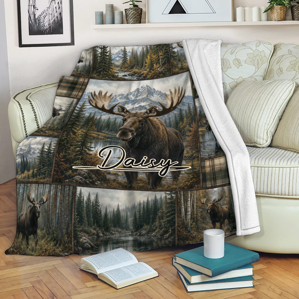 Moose blanket draped over a sofa with mountain, evergreen forest, lake, and wildlife artwork