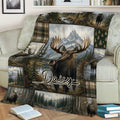 Close view of a moose throw blanket displayed on a sofa with scenic wilderness and mountain artwork