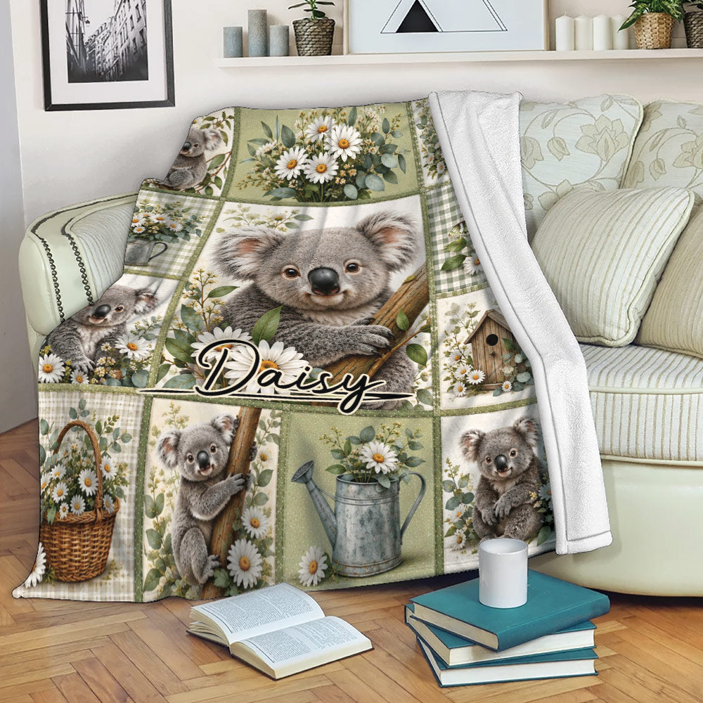 Koala floral throw blanket displayed on a sofa with repeating koala illustrations, daisies, and soft green accents
