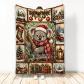 Christmas koala blanket featuring a Santa-hat koala, ornaments, snowy cabins, gifts, and festive greenery