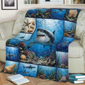 Shark throw blanket displayed across a couch with underwater scenes, seashells, and coral artwork