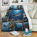 Shark throw blanket draped over a sofa with deep blue ocean artwork, coral reefs, fish, and starfish