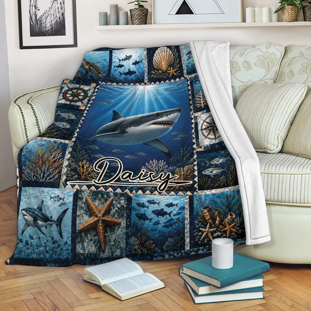 Shark throw blanket draped over a sofa with deep blue ocean artwork, coral reefs, fish, and starfish