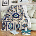 Blue Evil Eye throw blanket displayed on a sofa with Nazar symbols, leafy artwork, and ornate medallions