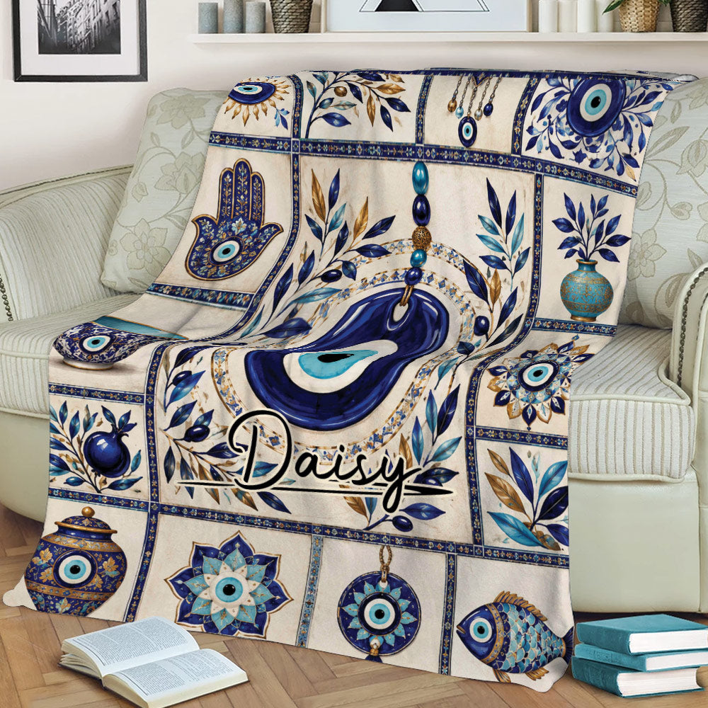 Evil Eye blanket draped over a sofa, featuring blue Nazar designs, Hamsa hands, pottery, and floral details
