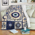 Evil Eye throw blanket draped over a sofa, featuring blue nazar talismans, botanical details, and celestial motifs