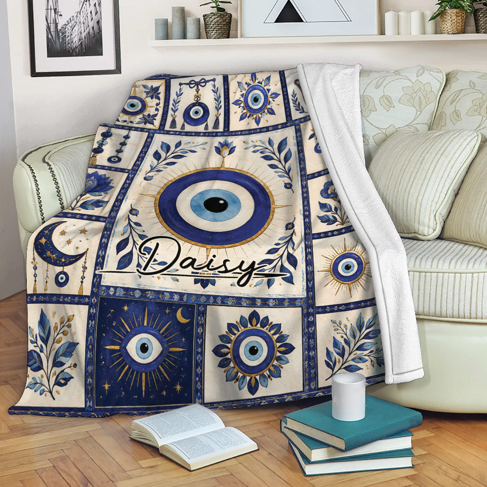 Evil Eye throw blanket draped over a sofa, featuring blue nazar talismans, botanical details, and celestial motifs