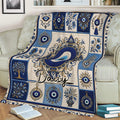 Decorative evil eye blanket draped across a sofa, featuring blue eyes, hamsa art, and botanical motifs