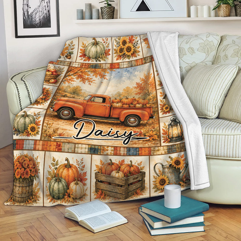 Fall throw blanket draped over a sofa with vintage truck, pumpkins, autumn leaves, and harvest design
