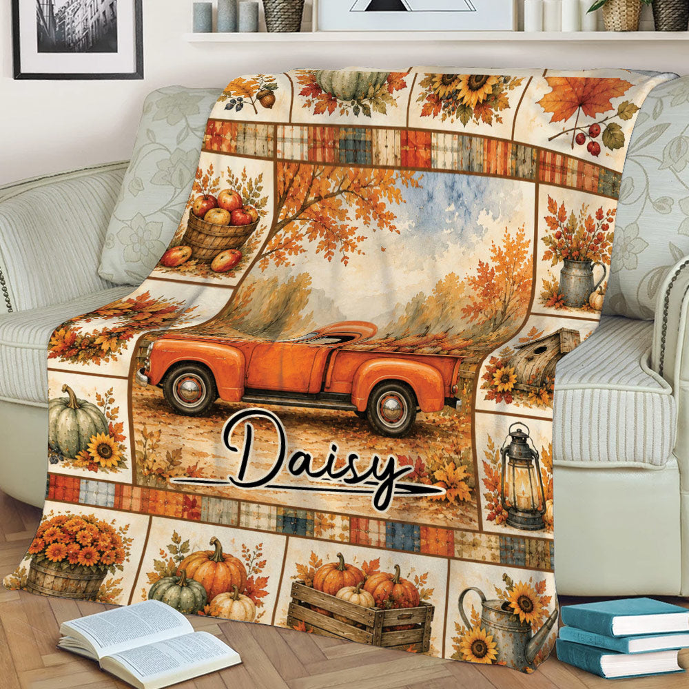 Cozy autumn blanket displayed on a sofa with pumpkin harvest, orange truck, sunflowers, and rustic fall artwork