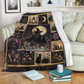 Witchcraft throw blanket displayed on a sofa with moon, witch, black cat, cauldron, candles, and mystical cottage motifs