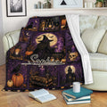 Witchcraft throw blanket draped over a sofa with purple gothic artwork, candles, books, pumpkins, and a witch