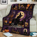 Purple witchcraft blanket displayed on a couch with a witch, moon, cauldron, broom, black cat, bats, and gothic decor