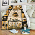 Bee blanket draped over a sofa with honey bee, sunflower, beehive and honeycomb artwork